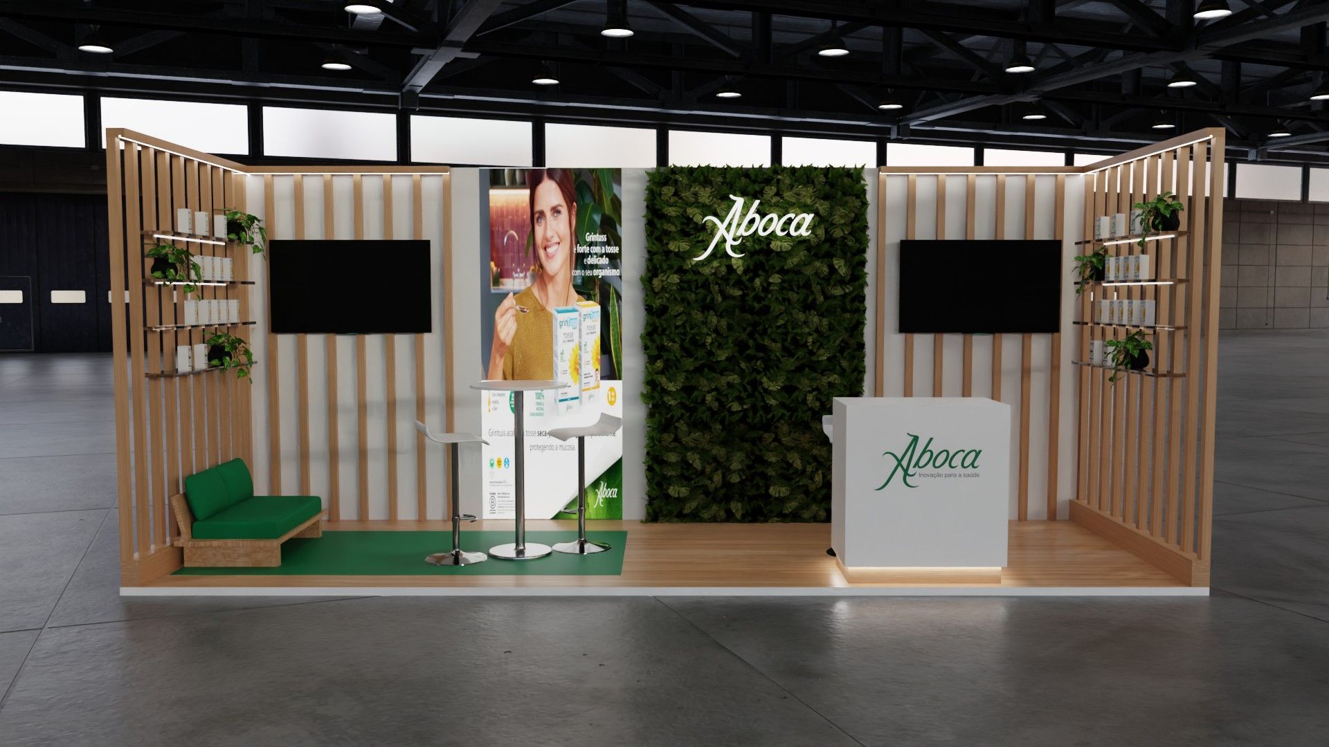 Stand Aboca em versão larga, simétrico, com dois ecrãs, jardim vertical central, sofá verde e balcão à direita.